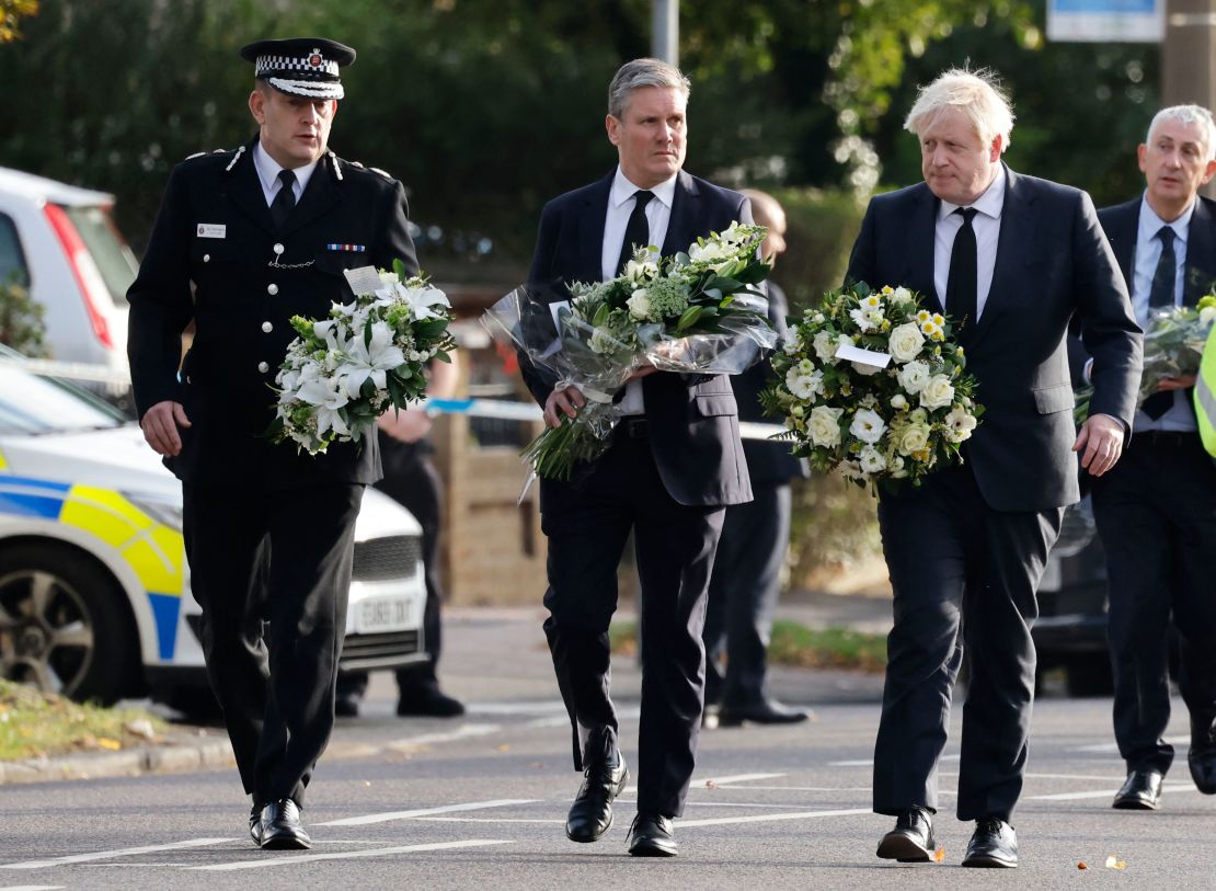 Britain's Prime Minister Boris Johnson (right), Britain's main opposition Labour Party leader Keir Starmer (center) and senior police officer Ben-Julian Harrington carry floral tributes to Belfairs Methodist Church in Leigh-on-Sea on Saturday.