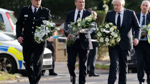 Britain's Prime Minister Boris Johnson (right), Britain's main opposition Labour Party leader Keir Starmer (center) and senior police officer Ben-Julian Harrington carry floral tributes to Belfairs Methodist Church in Leigh-on-Sea on Saturday.