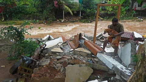 A resident carries a dog amid debris of his damaged house after flash floods caused by heavy rains at Thodupuzha, in India's Kerala state, on October 16.