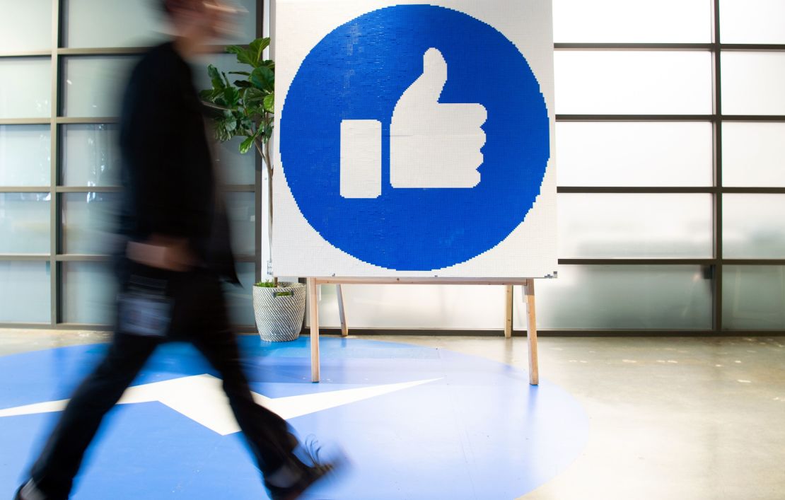 A Facebook employee walks by a sign displaying the "like" sign at Facebook's corporate headquarters campus in Menlo Park, California, on October 23, 2019. (Photo by Josh Edelson/AFP/Getty Images