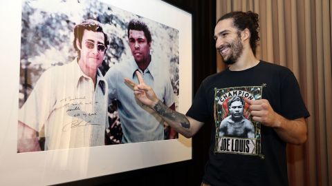 Ali Walsh visits with boxing promoter Bob Arum and poses in front of a photo of his grandfather.