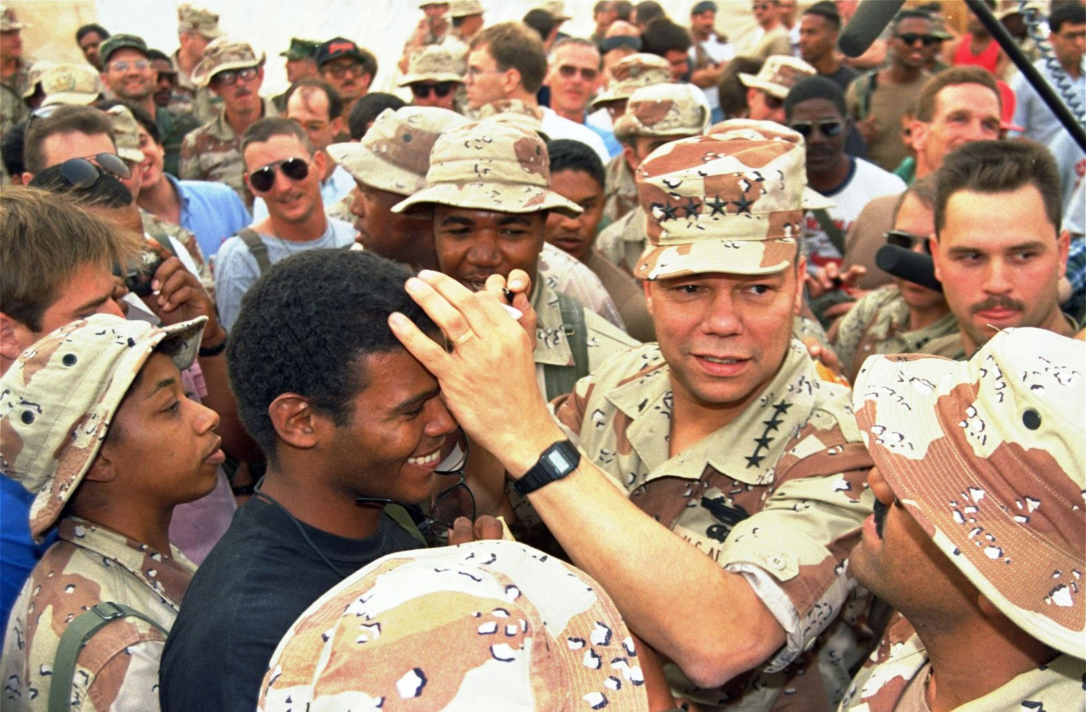 Powell playfully uses the head of Air Force Sgt. Thaddeus Fernandez while autographing a Saudi monetary note in 1990. Powell was visiting an Air Force base in San Antonio.