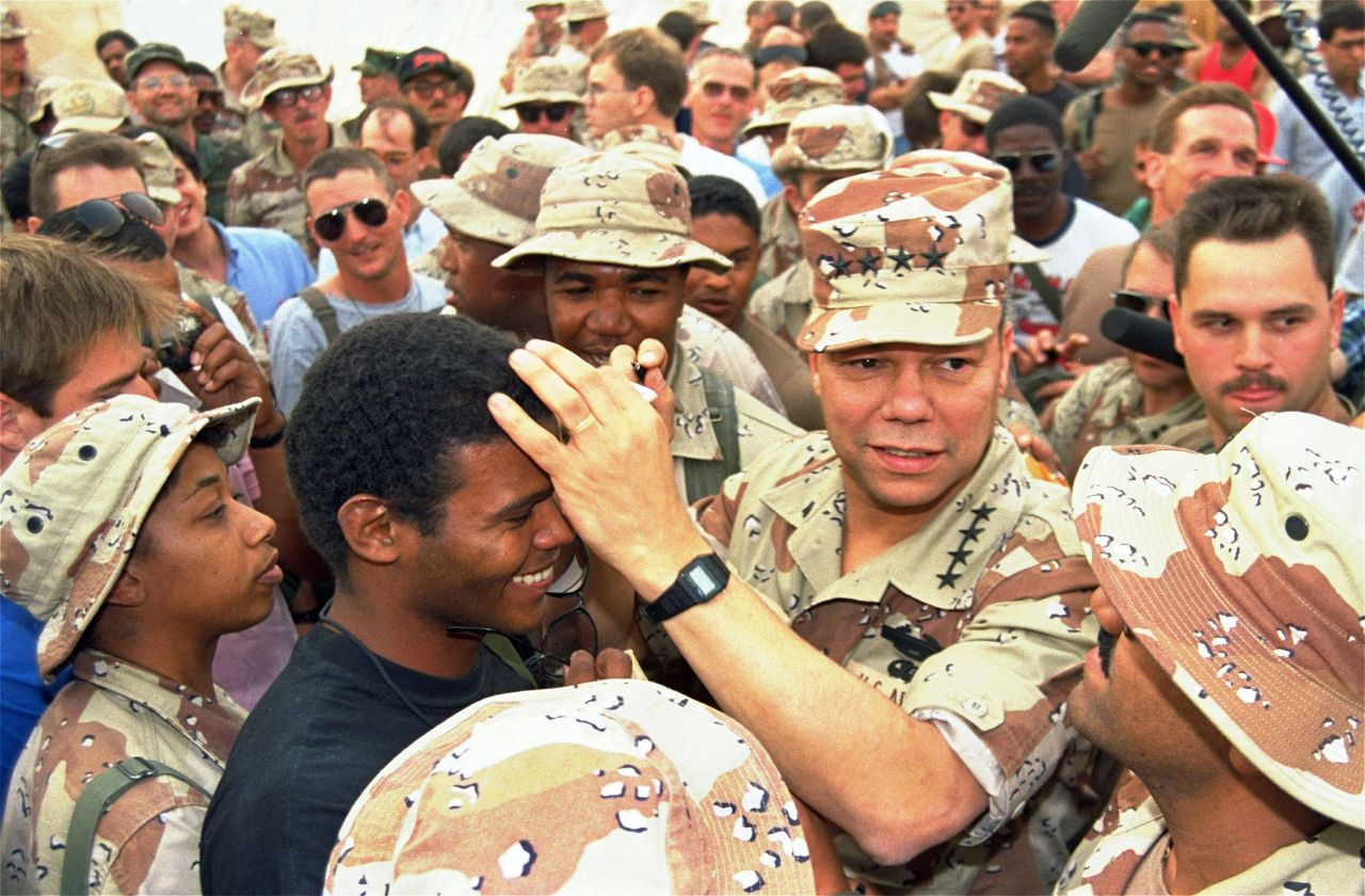Powell playfully uses the head of Air Force Sgt. Thaddeus Fernandez while autographing a Saudi monetary note in 1990. Powell was visiting an Air Force base in San Antonio.