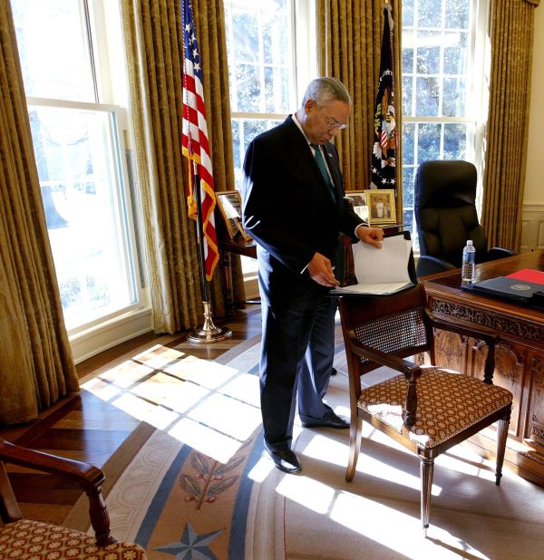 Powell reads over papers while standing in the Oval Office in 2004.