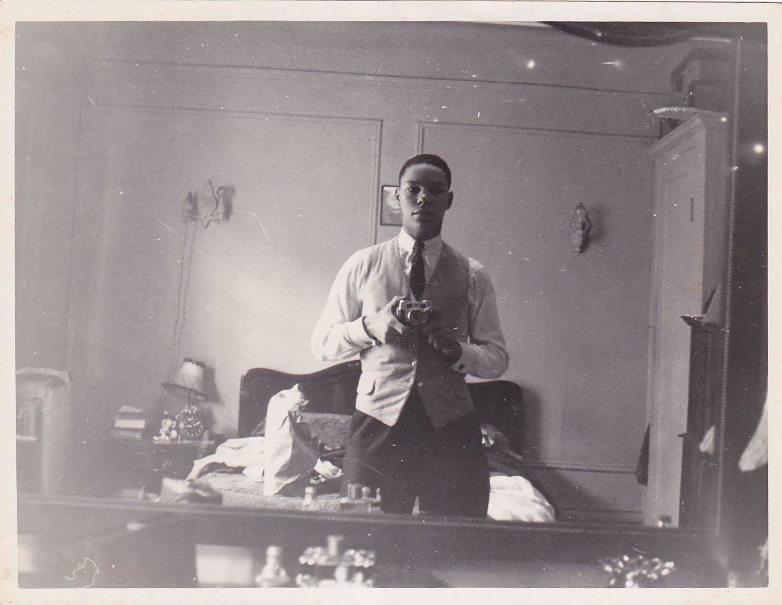 A young Powell takes a photo of himself in a mirror. Powell, a son of Jamaican immigrants, was born in Harlem, New York, in 1937 and grew up in the South Bronx. He attended the City College of New York, where he participated in ROTC, leading the precision drill team and attaining the top rank offered by the corps.