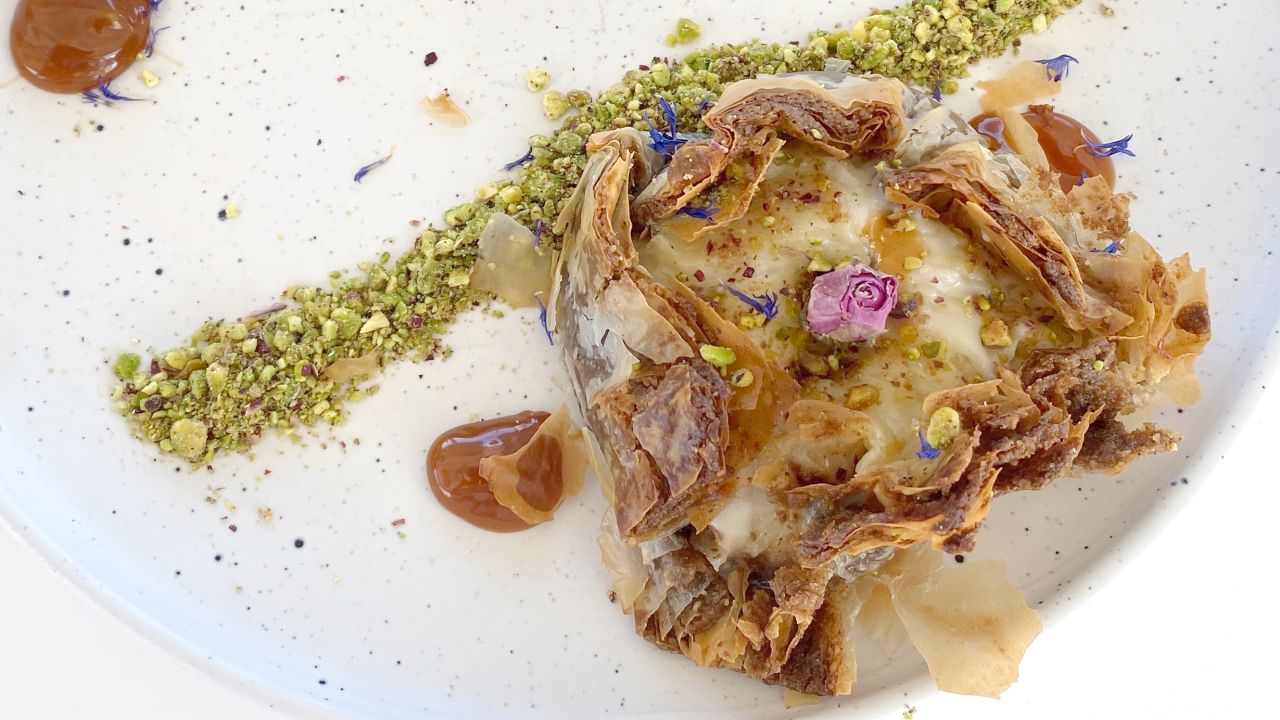 Traditional ruffled milk pie is artfully displayed with Greek pistachios and a rosebud.