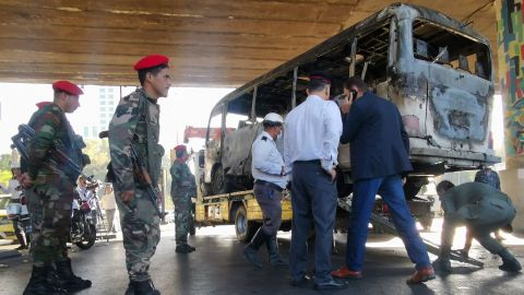 Security forces stand guard as the charred bus is removed from the site of the attack.