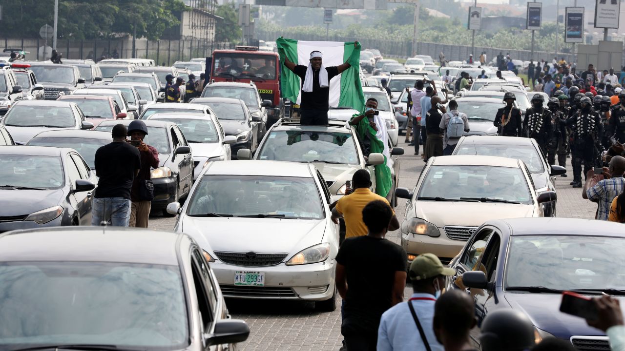 A demonstrator raises a Nigerian flag during a protest to mark the one-year anniversary of the Lekki Toll Gate massacre.