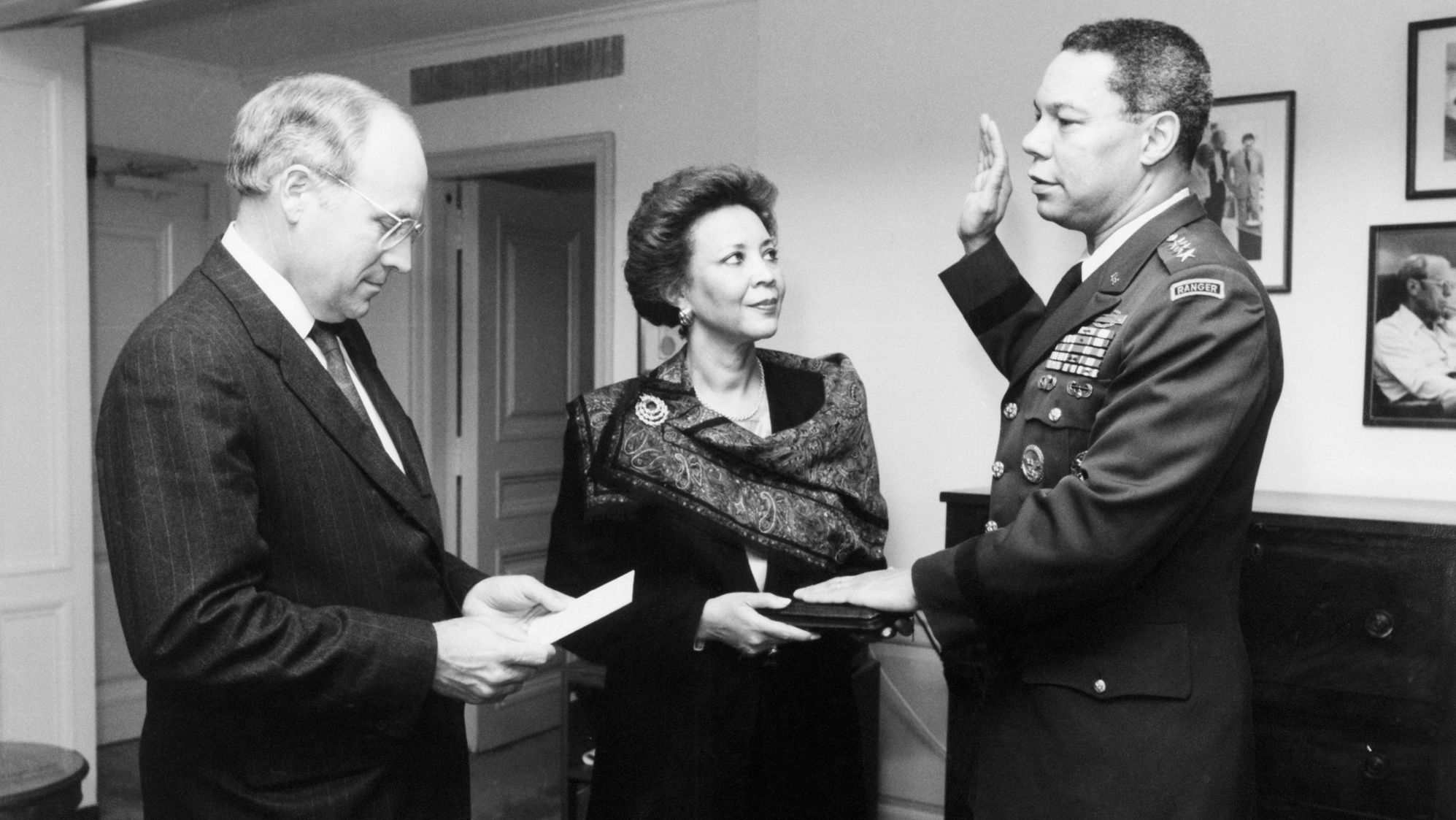 Secretary of Defense Dick Cheney administers the oath of office to Gen. Colin Powell as the chairman of the Joint Chiefs of Staff as Alma Powell holds the Bible.