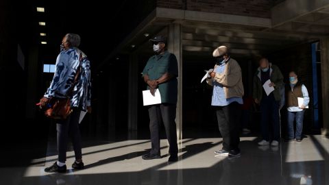 People wait in line with their paperwork to get coronavirus booster shots during a Pfizer/BioNTech vaccination clinic in Southfield, Michigan.