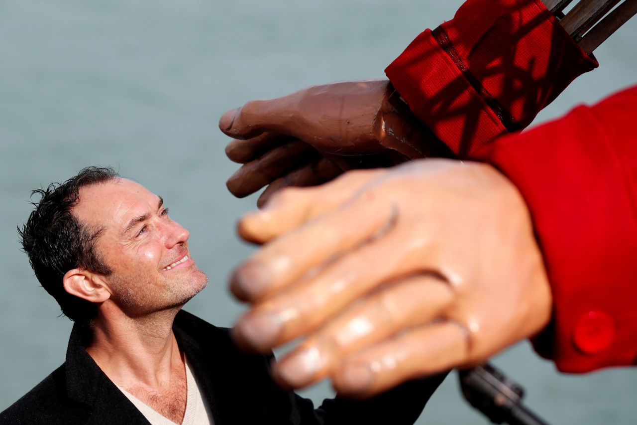 Actor Jude Law holds the hand of 'Little Amal', a 3.5 meter-tall puppet of a young Syrian refugee girl, during its tour across Europe on Tuesday, October 19, in Folkestone, Britain. The puppet's tour from Turkey to Britain is to raise awareness for the plight of young refugees.