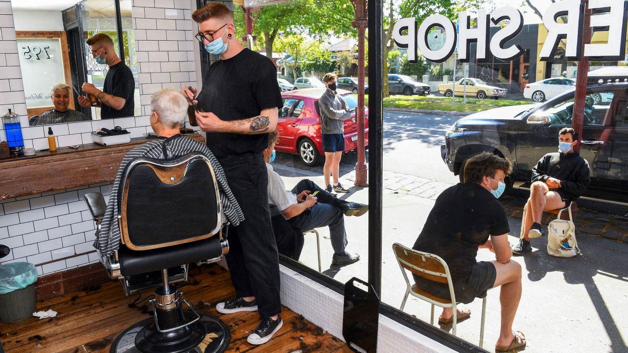 A barber gives a haircut as other customers wait outside in a queue that began as early as 4:30 a.m. in Melbourne on October 22.