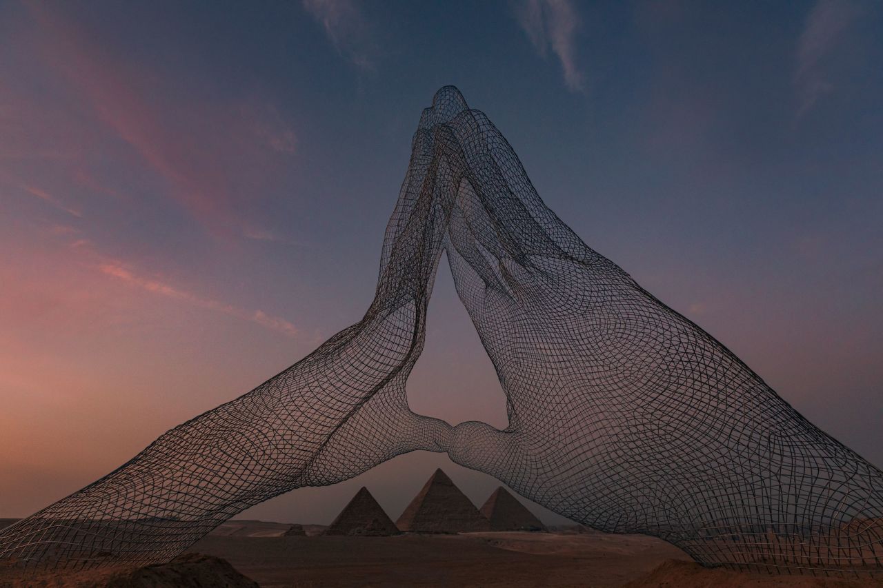 Two wireframe hands touch fingertips in Lorenzo Quinn's "Together."