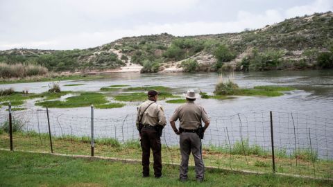 A pair of officers look out at the Rio Grande between Mexico and the United States in Del Rio, Texas this Spring.