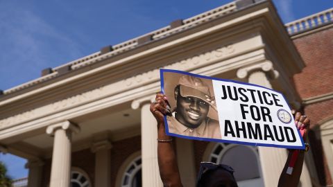A demonstrator holds a sign at the Glynn County Courthouse as jury selection begins in the trial of the shooting death of Ahmaud Arbery in Brunswick, Georgia. 