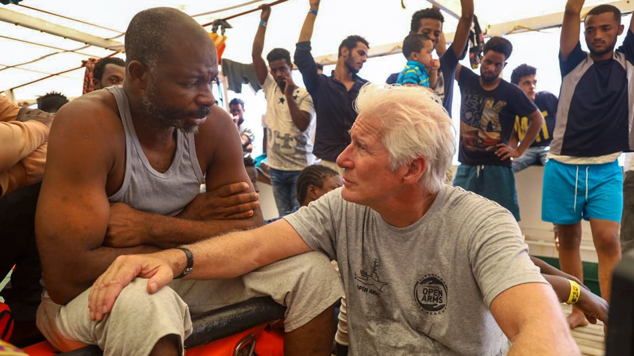 Actor Richard Gere, right, talks with migrants aboard the Open Arms Spanish humanitarian boat as it cruises in the Mediterranean Sea, Friday, Aug. 9, 2019.