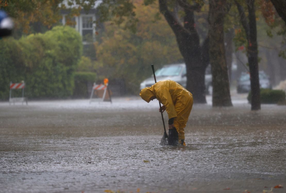 A worker tries to clear a drain in a flooded street Sunday in San Rafael, California, near the San Francisco Bay.
