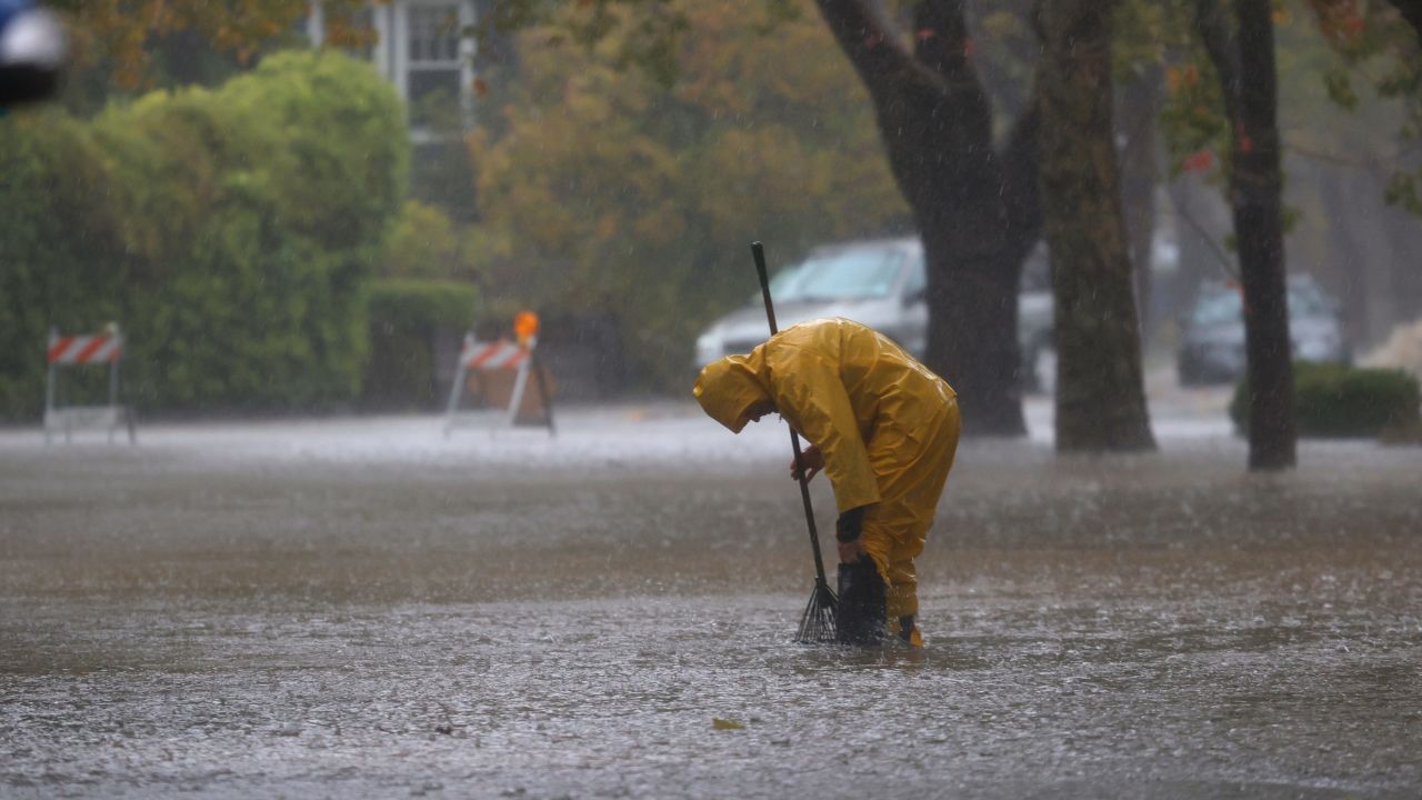 A worker tries to clear a drain in a flooded street Sunday in San Rafael, California, near the San Francisco Bay.