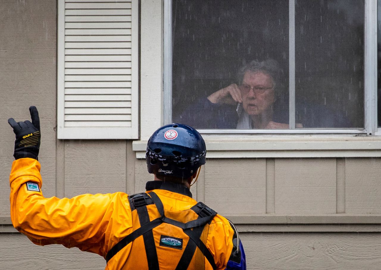 A firefighter persuades a resident to evacuate a flooded area in Santa Rosa, California, on Sunday.
