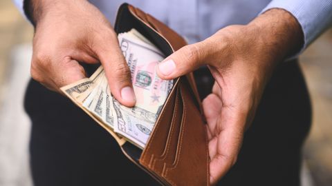 underscored cash in wallet with hands removing bills