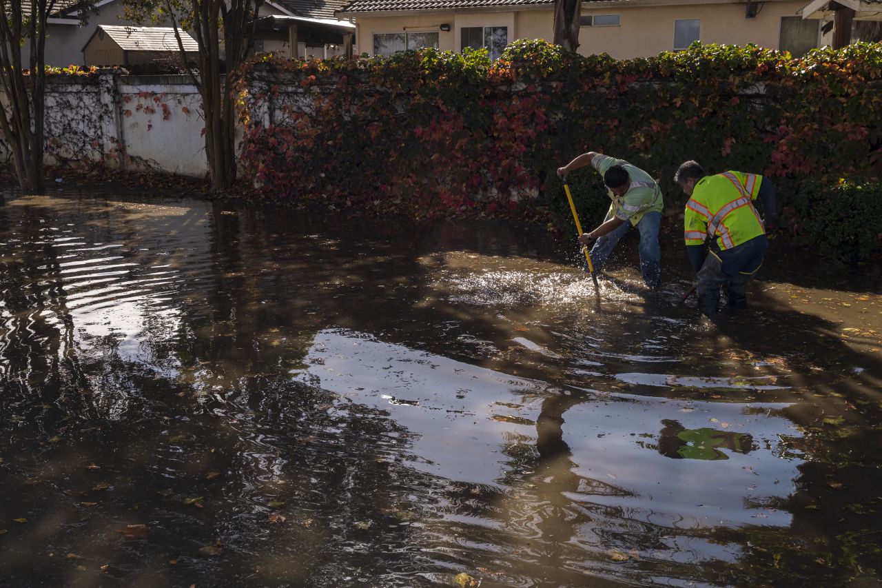 Workers clear floodwaters in Hollister, California, on Monday.