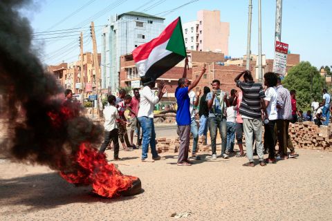 Protesters who oppose the coup in Sudan raise national flags and burn tires on a street in Khartoum, Sudan, on Tuesday, October 26.