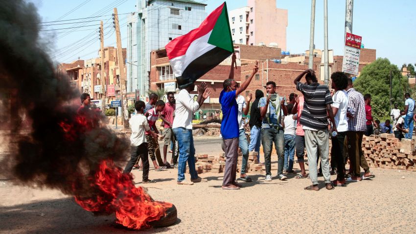 Sudanese demonstrators lift national flags and burn tyres on a street in the capital Khartoum, on October 26, 2021, as they protest a military coup that overthrew the transition to civilian rule. - Angry Sudanese stood their ground in street protests against a coup, as international condemnation of the military's takeover poured in ahead of a UN Security Council meeting. (Photo by AFP) (Photo by -/AFP via Getty Images)