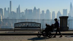 A woman pushes a stroller as the New York skyline is seen from Weehawken, New Jersey on November 9, 2020. 