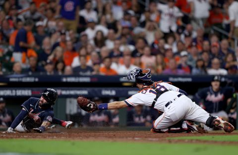 The Braves' Dansby Swanson slides in safely past the Astros' Jason Castro to score a run on a sacrifice fly during the eighth inning in Game 1.