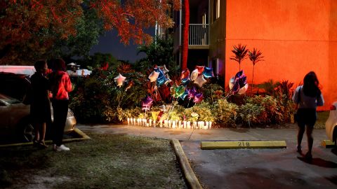People stand near the memorial on the spot where 18-year-old Dwight "DJ" Grant's body was found near his home at the New Park Towers apartment complex on October 26 in Miramar, Florida. 