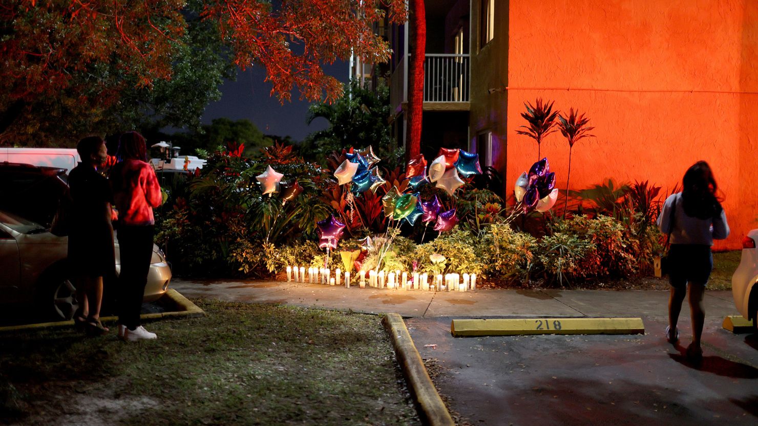 People stand near the memorial on the spot where 18-year-old Dwight "DJ" Grant's body was found near his home at the New Park Towers apartment complex on October 26 in Miramar, Florida. 