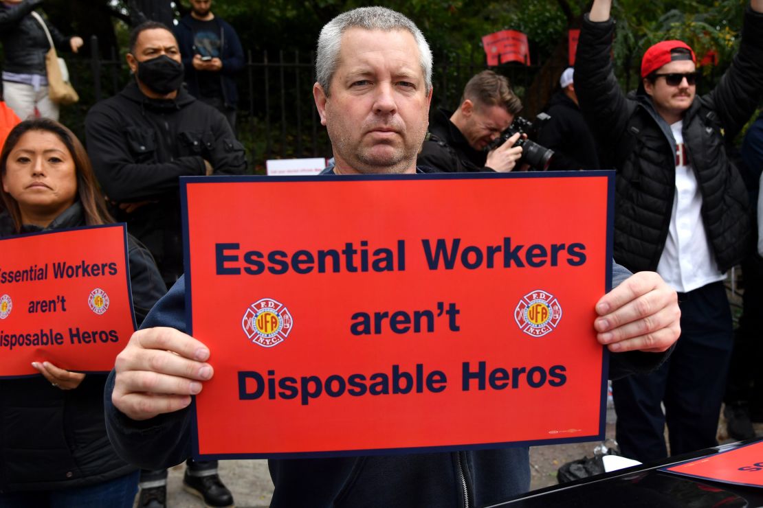 A protester at Thursday's rally holds a sign that reads, "Essential Workers aren't Disposable Heros." 