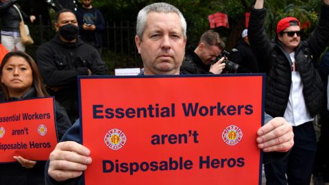 A protester at Thursday's rally holds a sign that reads, "Essential Workers aren't Disposable Heros."