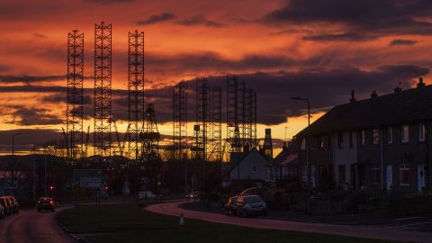 Jackup rigs used in the North Sea oil and gas industry are silhouetted against the sky at sunset over the Port of Dundee.