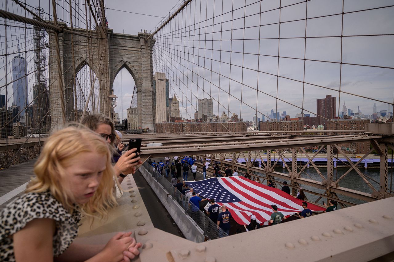 Municipal workers hold placards and shout slogans as they march across the Brooklyn Bridge on Monday, October 25, to protest <a href="https://www.cnn.com/2021/10/20/us/nyc-vaccine-mandate-extension/index.html" target="_blank">New York City's vaccine mandate.</a> The mandate covers all municipal workers.