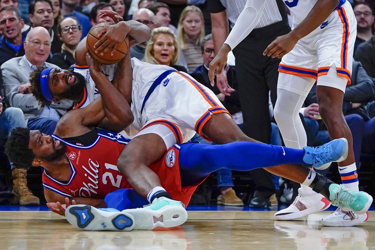Philadelphia's Joel Embiid, left, and New York's Mitchell Robinson fight for a loose ball during an NBA game in New York on Tuesday, October 26.