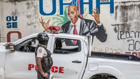 A police officer stands near a mural of the late Haitian President Jovenel Moïse, who was assassination in July 2021.