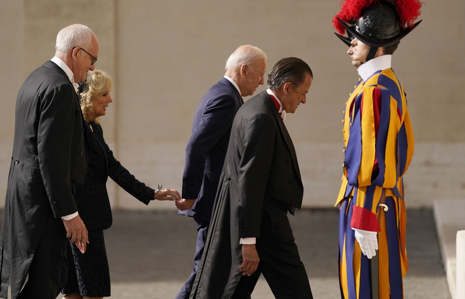 First lady Jill Biden reaches out to touch the President's hand as they arrive for their meeting with Francis.