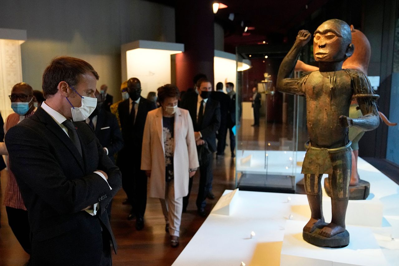 French President Emmanuel Macron inspects a 19th-century royal statue representing King Ghezo, exhibited at the Quai Branly museum before it is returned to Benin. 