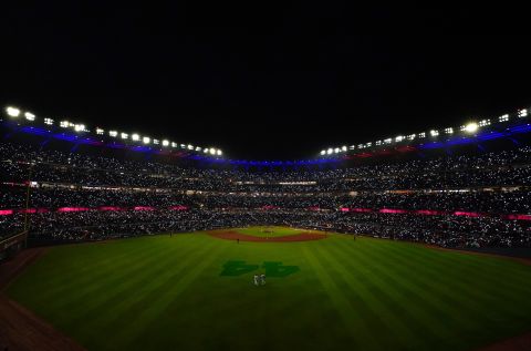 Fans hold up phone lights during a pitching change.
