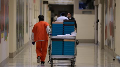 A detainee worker moves a cart of trays containing chicken fajita meals to be served to detainees during a media tour of the ICE detention center in Tacoma, Washington, in 2019.