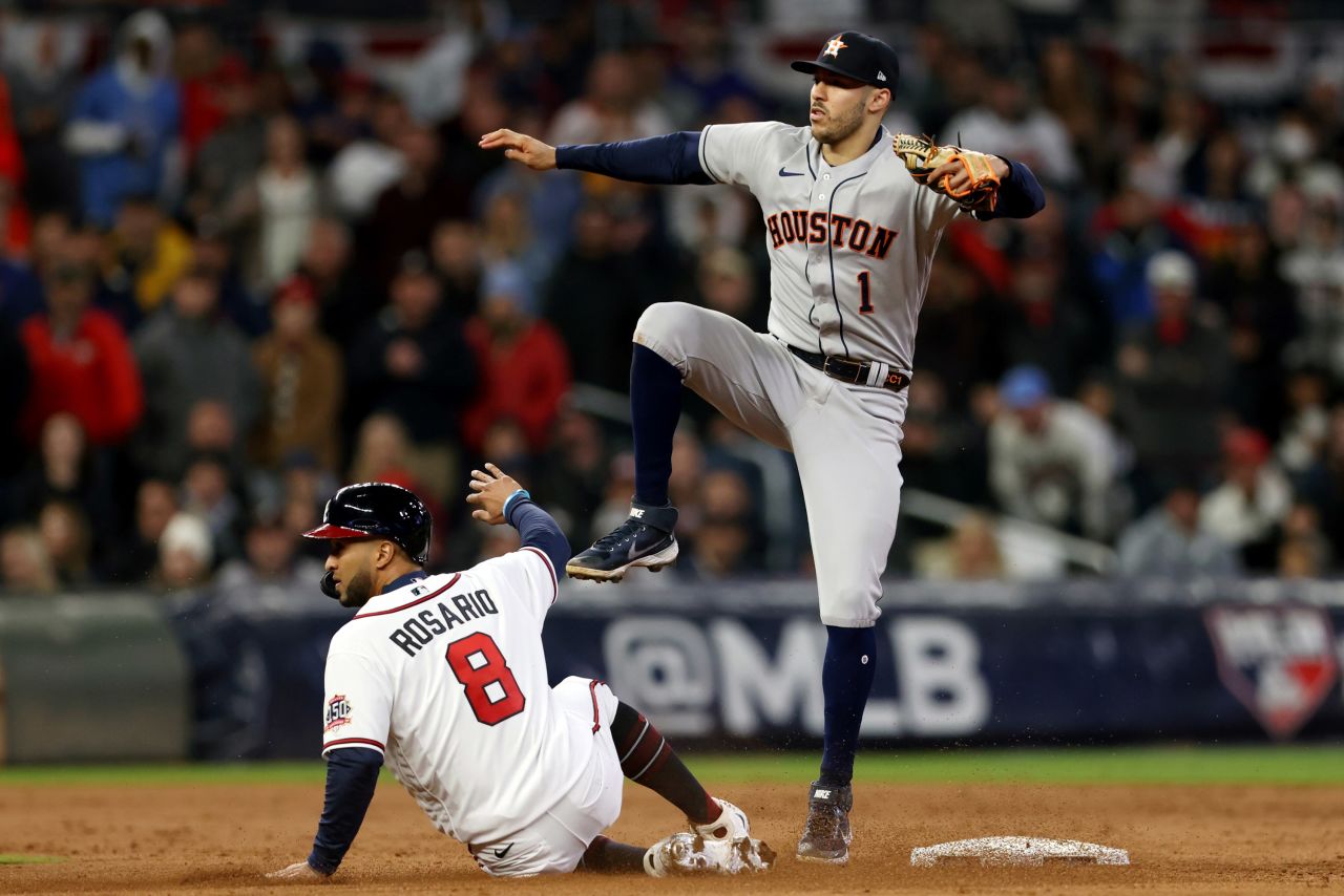 Carlos Correa of the Astros turns a double play as the Braves' Eddie Rosario slides into second base on Saturday.