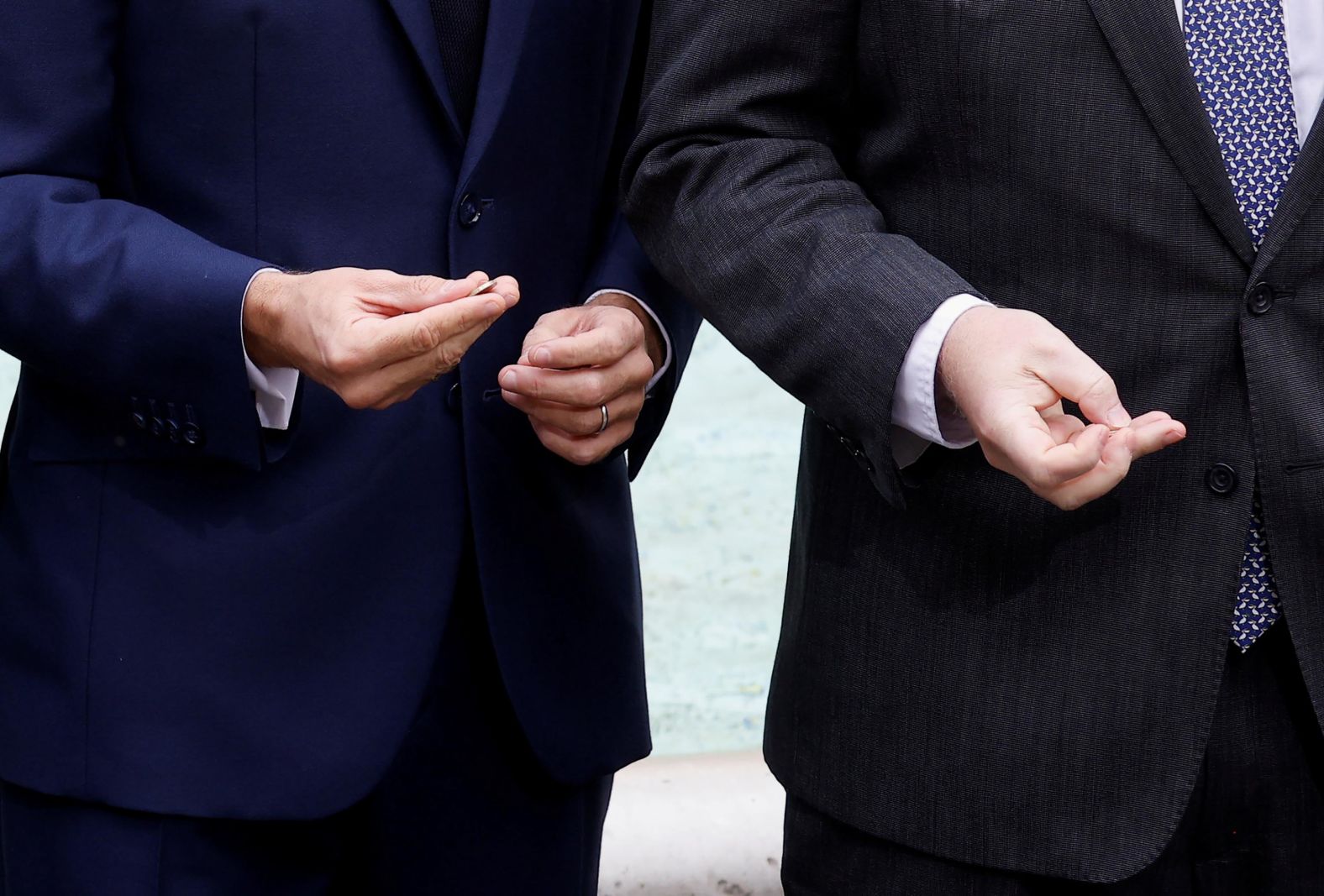 British Prime Minister Boris Johnson and French President Emmanuel Macron hold coins in front of the Trevi Fountain.