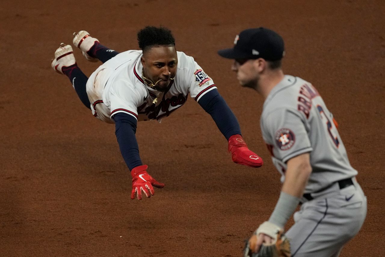 Braves second baseman Ozzie Albies dives into third past Astros third baseman Alex Bregman advancing on a double by Austin Riley on Sunday.