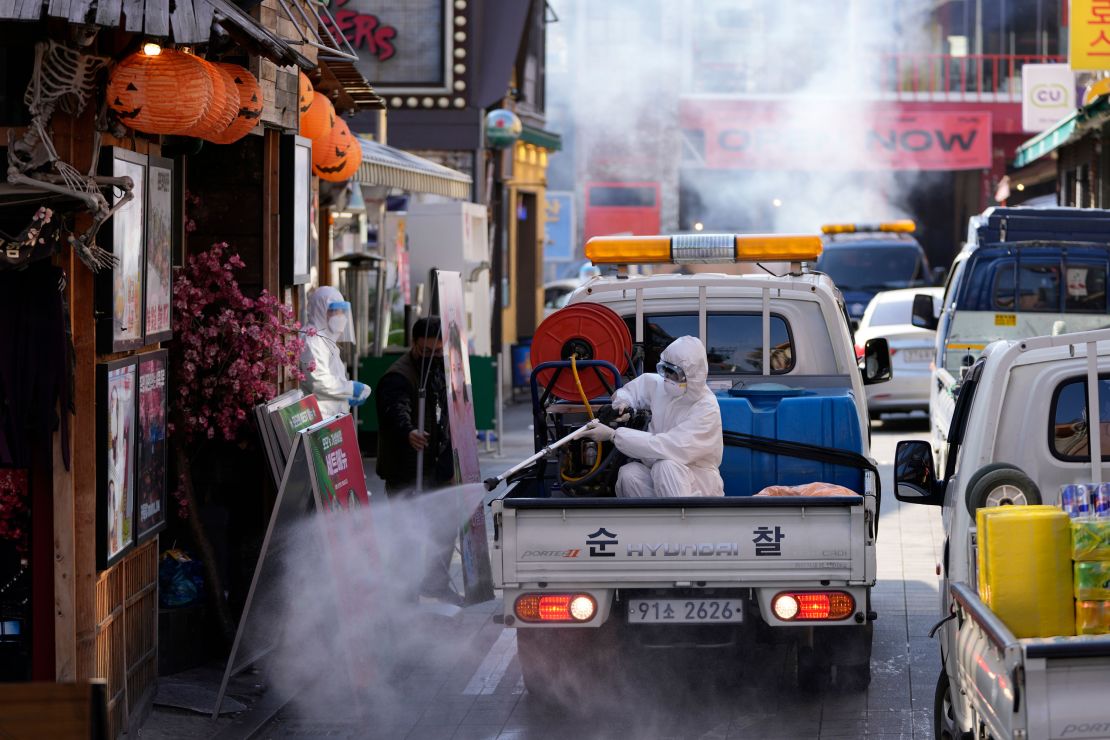 A local district health official in protective gear disinfects shop fronts as a precaution against the coronavirus in Seoul, South Korea, Friday, October 29.