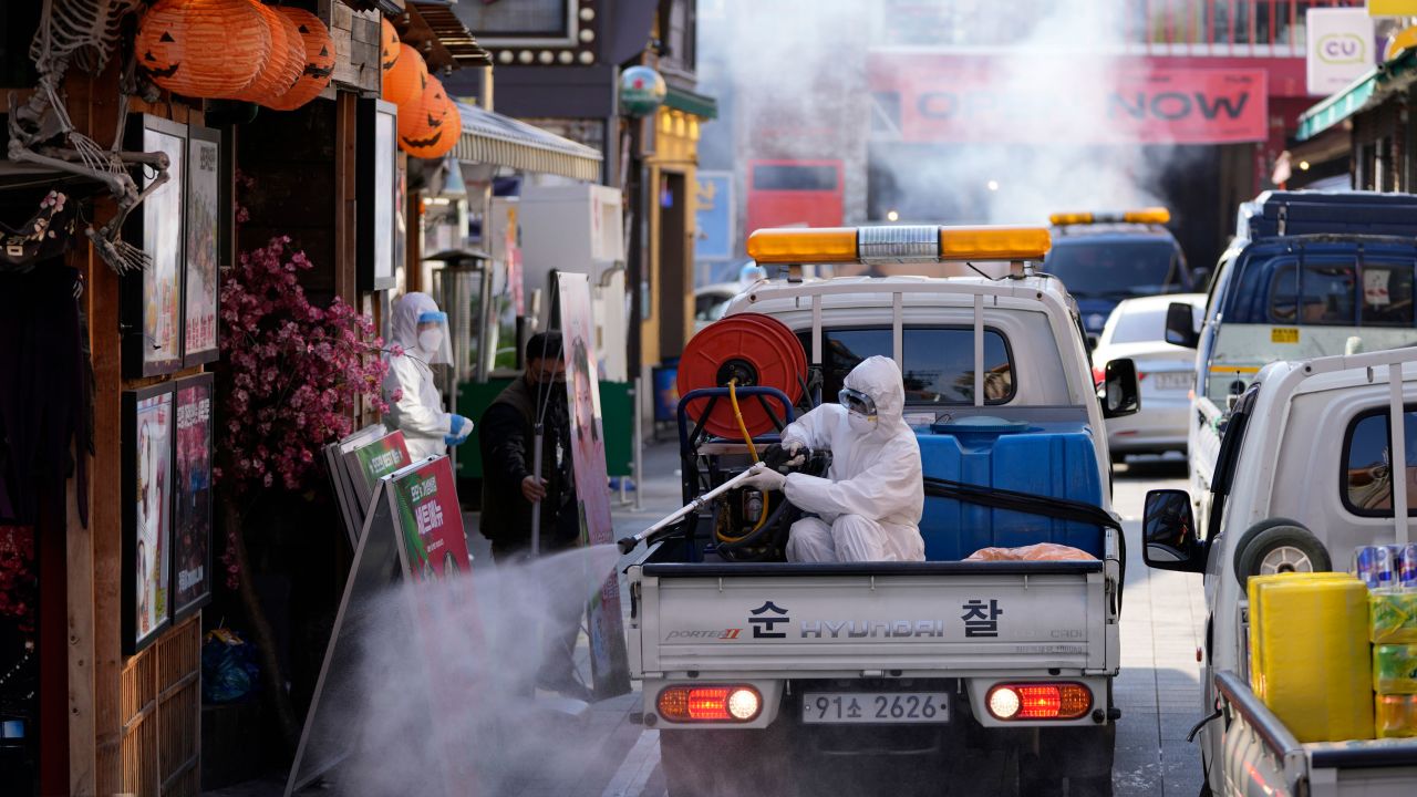 A local district health official in protective gear disinfects shop fronts as a precaution against the coronavirus in Seoul, South Korea, Friday, October 29.