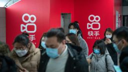Passengers wearing protective masks walks past Kuaishou Technology advertisements at a subway station in Beijing, China, on Wednesday, Feb. 3, 2021. Kuaishou Technology, the operator of China's most popular video service after ByteDance Ltd.'s Douyin, raised HK$42 billion ($5.4 billion) after pricing its Hong Kong initial public offering at the top of a marketed range. Photographer: Yan Cong/Bloomberg via Getty Images