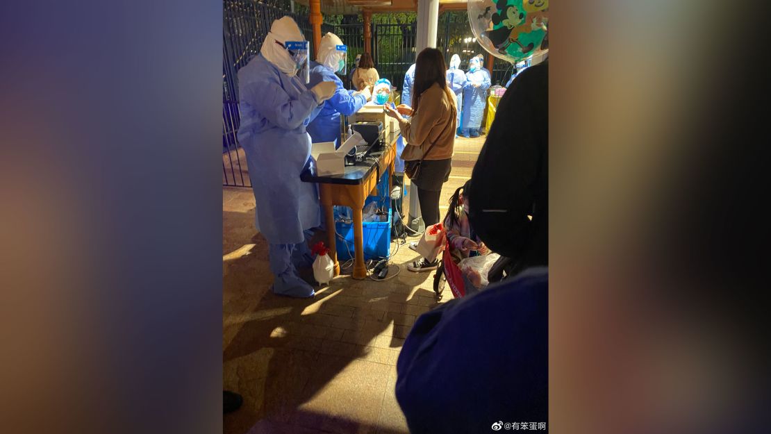 Shanghai Disneyland visitors queue for Covid-19 testing after the park announced a snap lockdown on Sunday.