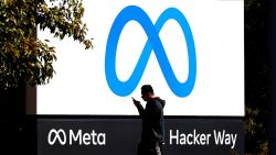 A pedestrian walks in front of a new logo and the name 'Meta' on the sign in front of Facebook headquarters on October 28, 2021 in Menlo Park, California. A new name and logo were unveiled at Facebook headquarters after a much anticipated name change for the social media platform.