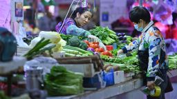 This photo taken on November 1, 2021 shows a resident buying vegetables at a market in Nanning, in China's southern Guangxi region.